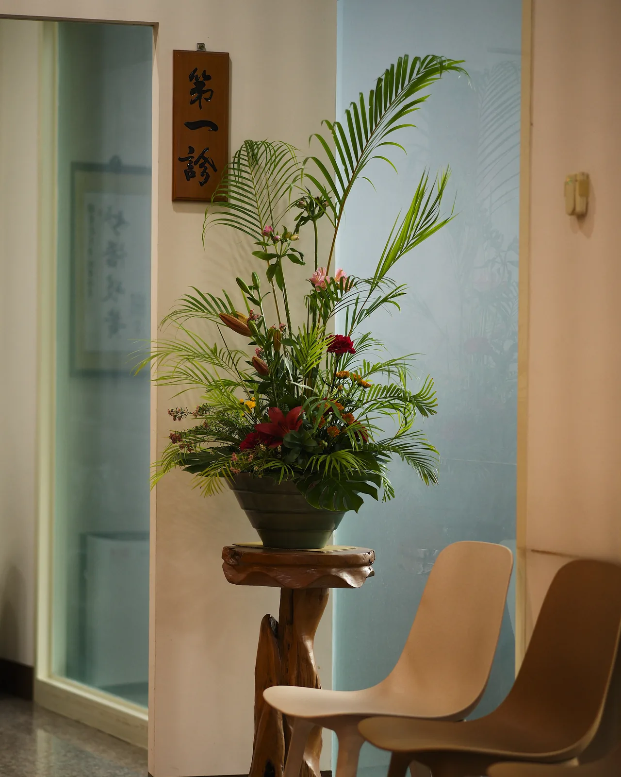 第一診間門口的原木花架上擺著一盆插花,門邊掛著「第一診」木牌