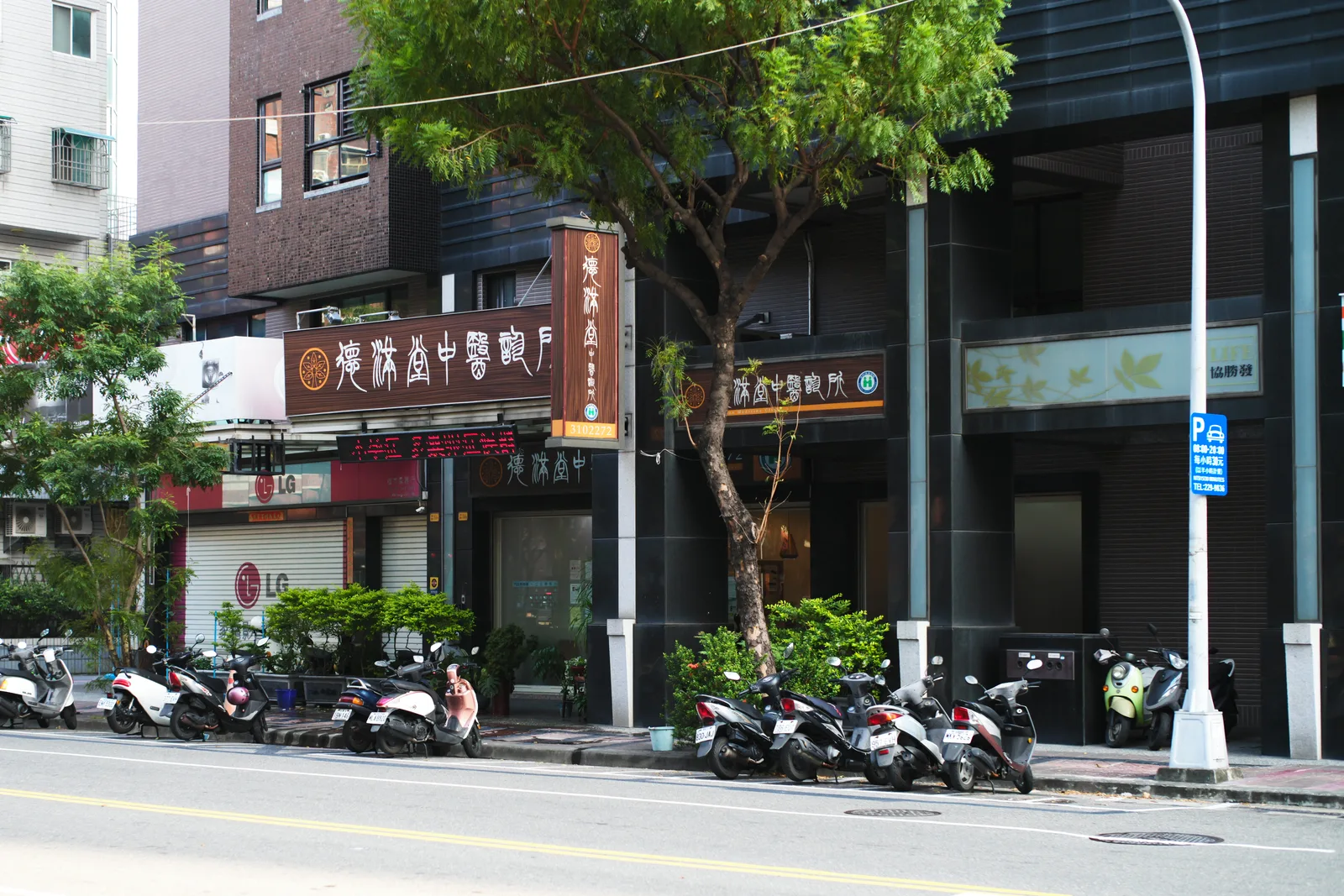 從對街看診所所在的大樓，一樓門面掛著直式與橫式招牌
