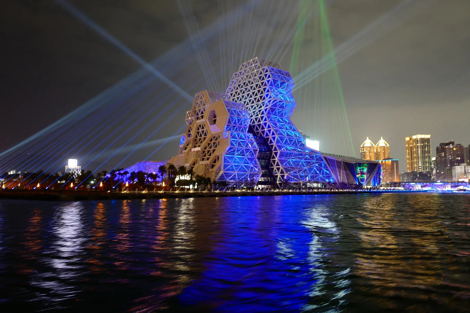 劉文法醫師攝影作品,夜景水面遠眺高雄流行音樂中心與雷射光束